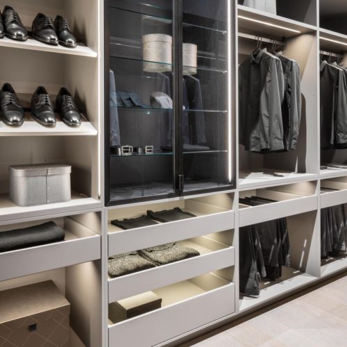 alt="Walk-in LEICHT closet with super matte-lacquer cabinetry, VERO glass shelves and inset strip LED lighting"