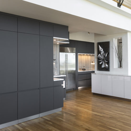 alt="corner view of whole kitchen showing carbon gray matte satin lacquer cabinets and island with arctic white gloss paneling"