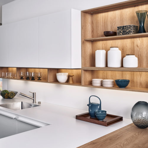 alt="View of kitchen uppers with SYNTHIA wood laminate shelves and BONDI white matte-lacquer cabinet face"