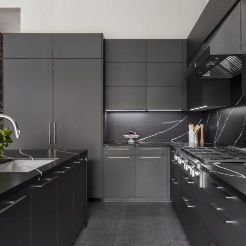 alt="Side view of upper, lower, and tall cabinets in carbon gray matte satin lacquer with inset strip LED lighting"