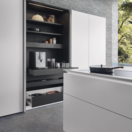alt="Close up of CLASSIC-FS matte-lacquer stand along cabinet fronts with open doors showing hidden storage and appliance"