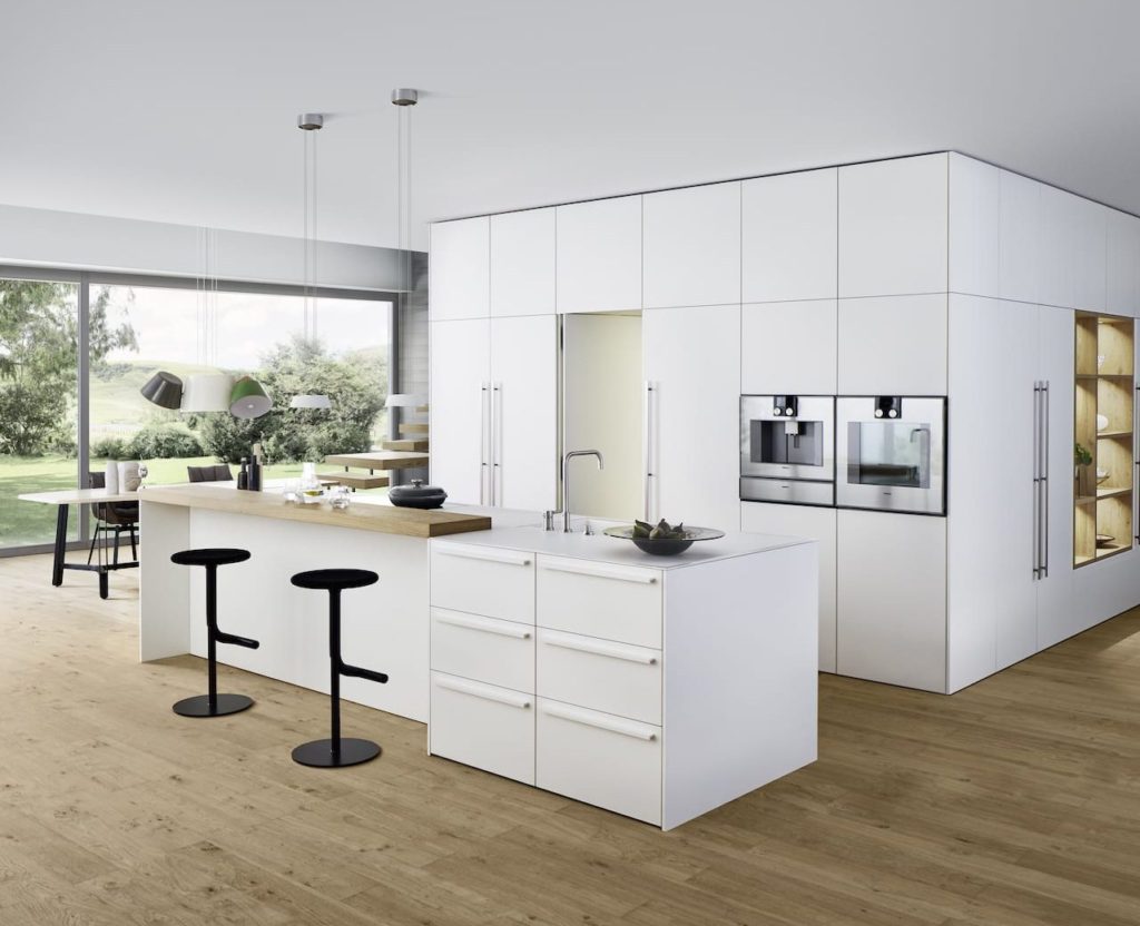 alt="Frontal kitchen view of work top, BONDI white matte-lacquer cabinet fronts, and shelving with XYLO genuine wood veneers"