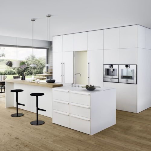 alt="Frontal kitchen view of work top, BONDI white matte-lacquer cabinet fronts, and shelving with XYLO genuine wood veneers"