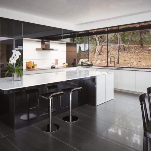 alt="Side view of kitchen showing gloss black glass cabinets and matte white glass cabinets"