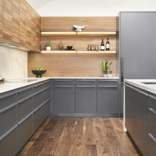 alt="Side kitchen view of carbon gray satin lacquer cabinets and talls with Tennessee walnut upper cabinet and wall veneer"