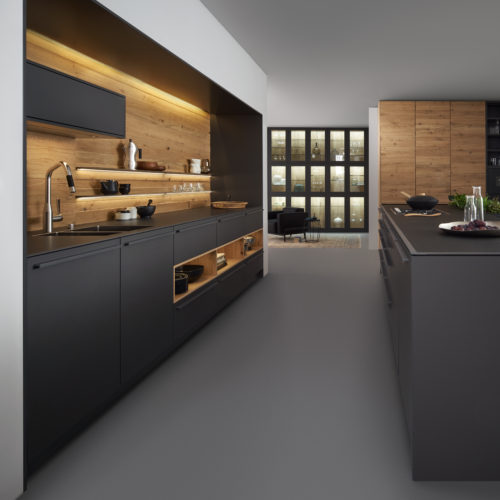 alt="Kitchen side view of BONDI super matte-lacquer lowers and island with VALAID genuine wood front on backsplash and floor to ceiling cabinets"