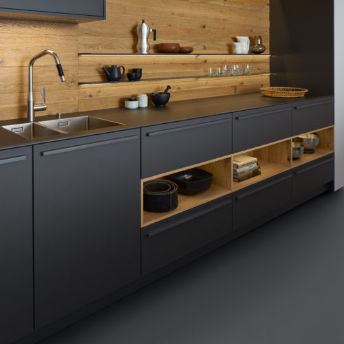 alt="Side view of worktop with sink showing uniform BONDI matte-lacquer front drawers with griprail handles and VALAIS wood back splash and shelf siding"