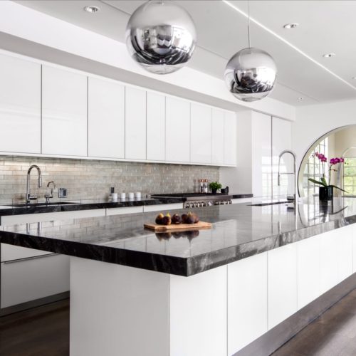 alt="Full kitchen view with IOS white glass cabinets, silver hanging lights, and circle doorway"