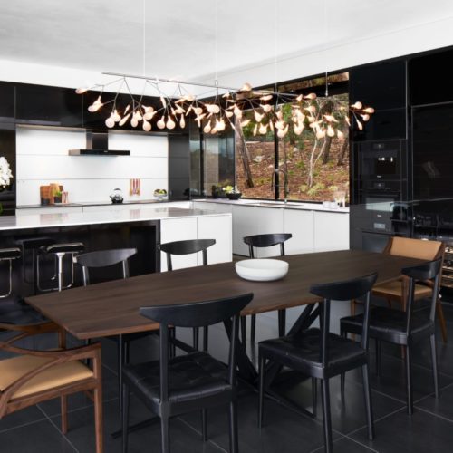 alt="Full kitchen and dining room view showing black gloss IOS glass wall cabinets and white matte glass lower cabinets"