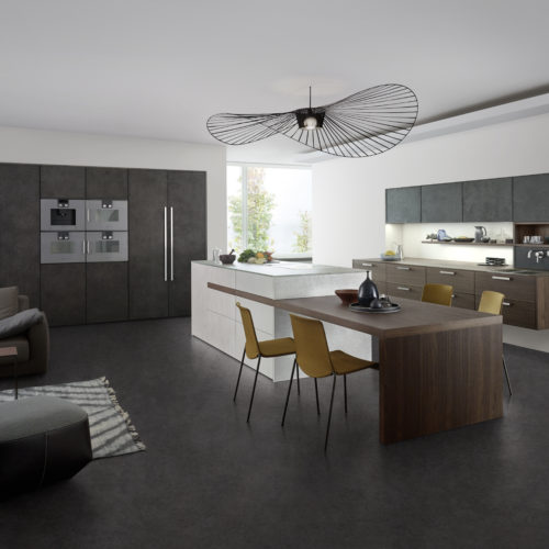 alt="Full kitchen view showing oven wall and upper cabinets with dark concrete font, island with light concrete front, and hanging cabinets with TOPOS wood veneer"