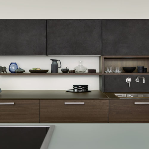 alt="Partial kitchen view of upper cabinets with concrete surface and lower island drawers with TOPOS wood veneer in walnut"