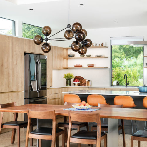 alt="full kitchen view of handle-less karst oak cabinets, open shelves, and integrated lighting"