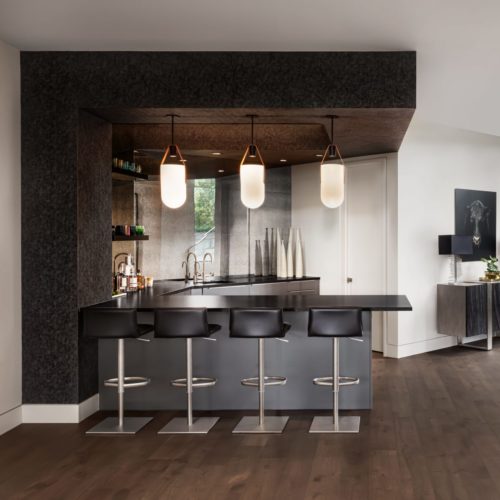alt="Wet bar with dark metal cabinets and glossy glass work top"