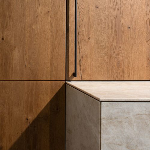alt="close up of island with ROCCA quartzite fronts with beveled edges and cabinet doors with MADERO oak veneers"