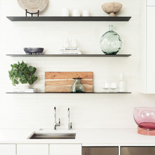 alt="close up view of work top with highgloss cabinets and floating black shelves"