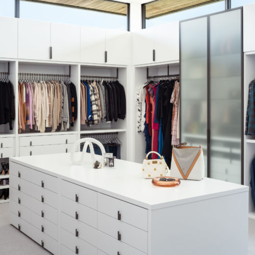 alt="Primary closet featuring matte lacquer cabinetry with gunmetal hardware and gunmetal framed frosted glass talls"