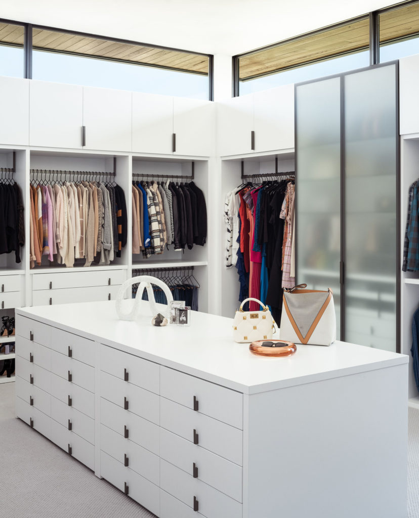 alt="Primary closet featuring matte lacquer cabinetry with gunmetal hardware and gunmetal framed frosted glass talls"