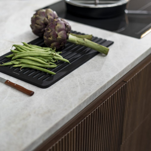 alt=”BOSSA: Close up of island walnut veneer and stove top with vegetables”