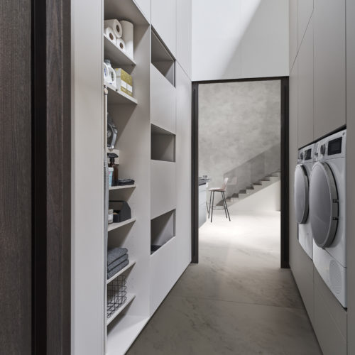 alt="Interior view of hidden laundry room with handleless fronts"